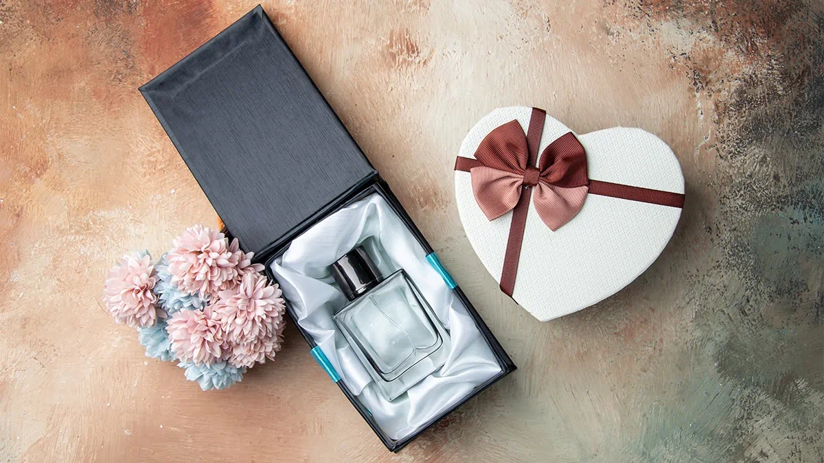 Perfume between a heart shape gift and artificial floral  