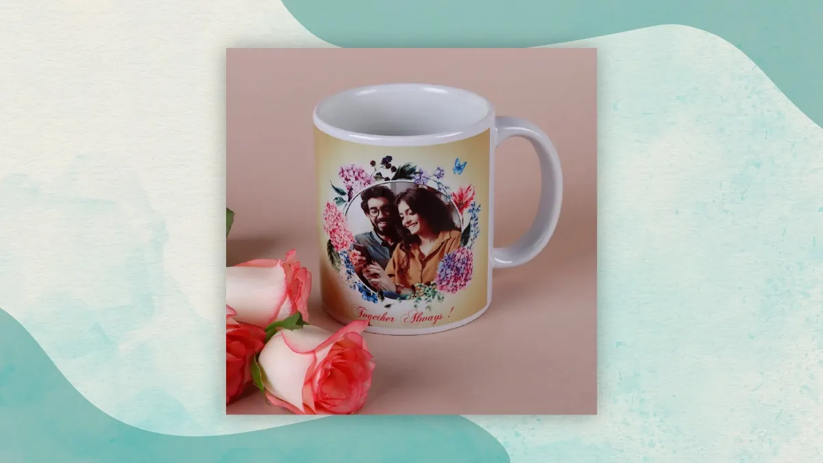 A personalized mug printed with a couple photo on it, kept beside two pink colored roses as gifts for long distance relationships. 