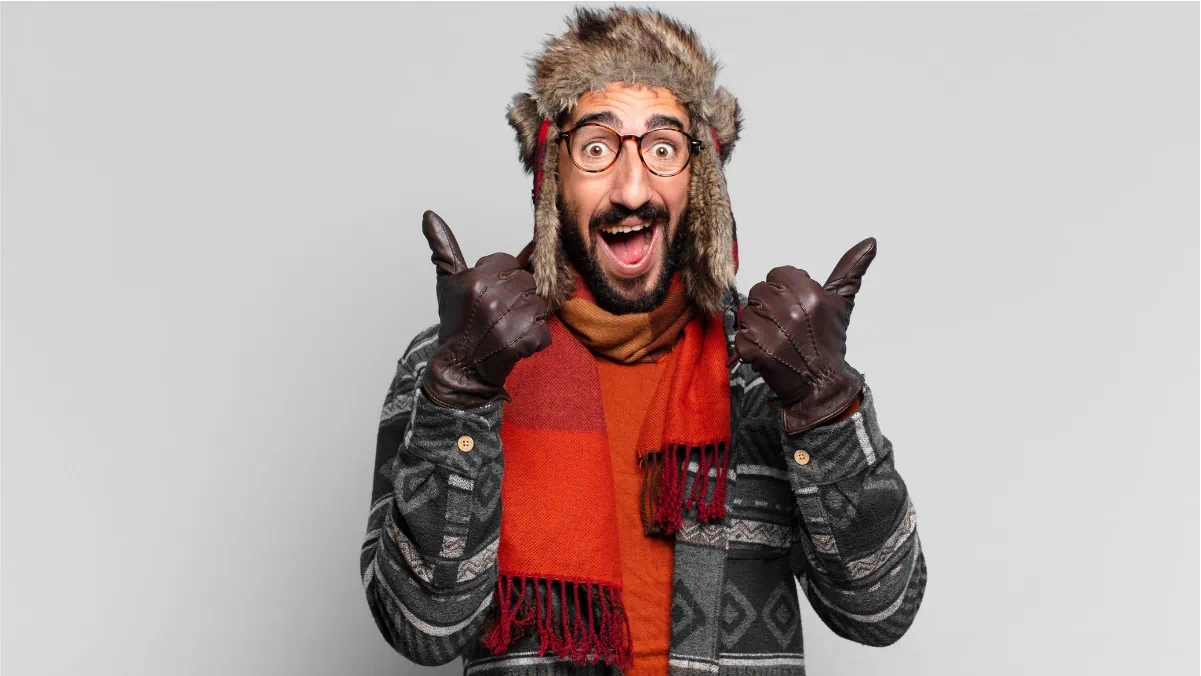 A happy man in a black sweater expressing his happiness on wearing a nice winter gloves.