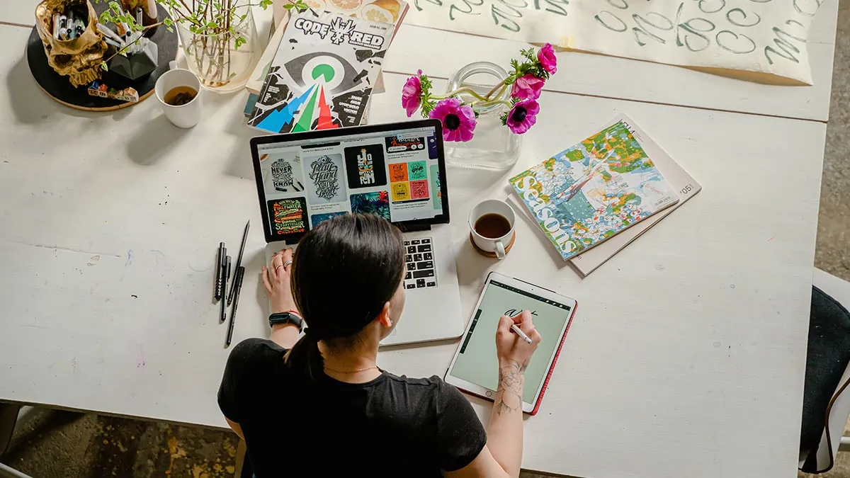 A woman using both traditional and digital tools to make art. 