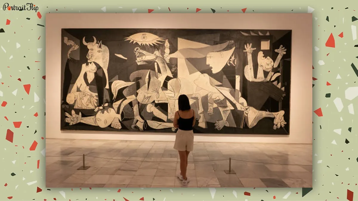 A woman looking at the Guernica painting of Pablo Picasso in a museum. 