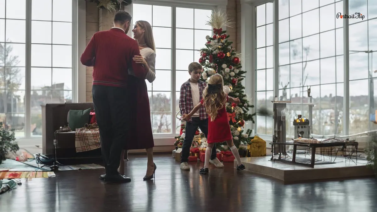 a family dancing in front of the christmas tree