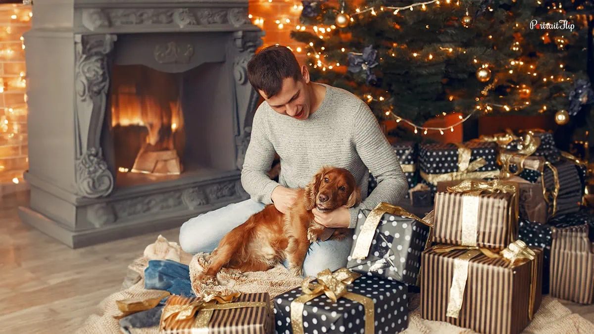 a man with his dog under the christmas tree
