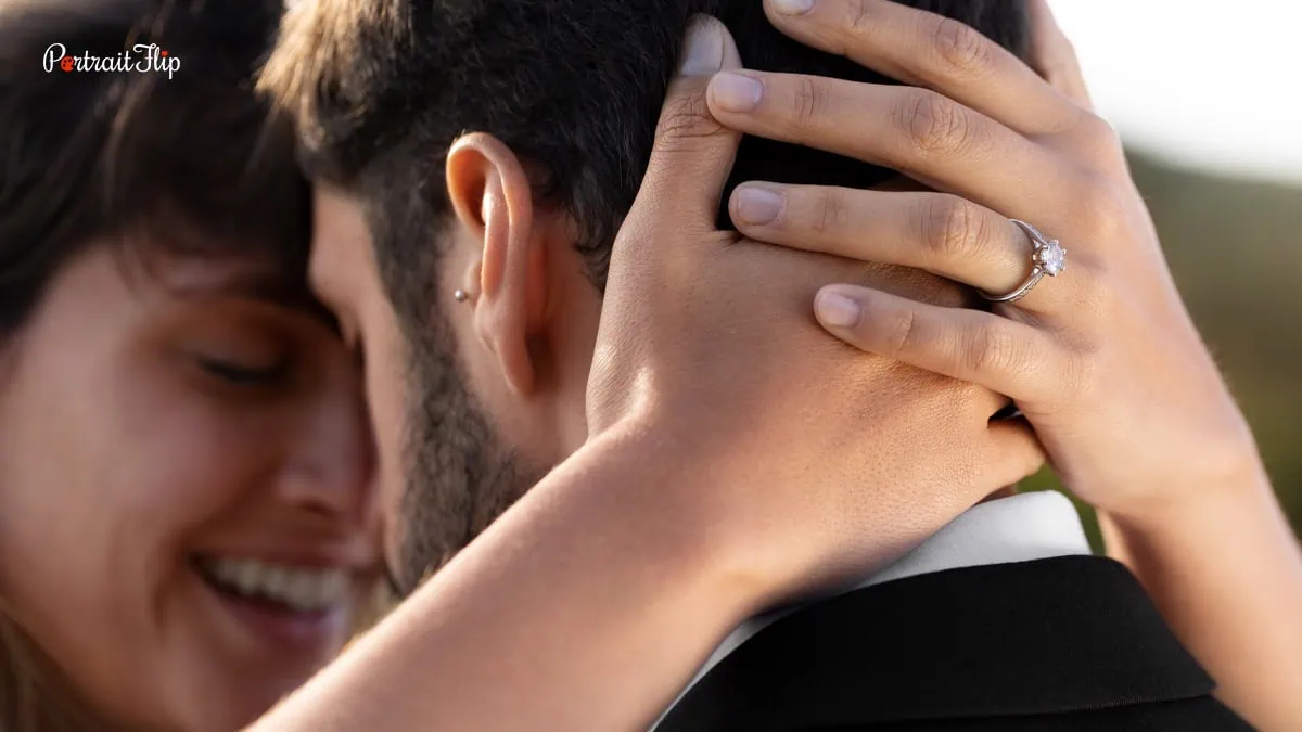 In this image you can see a closeup shot of a woman and a man showing the woman's ring.