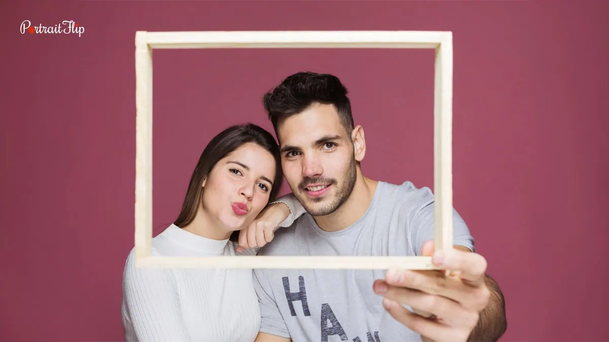 This image shows a young couple holding frame and posing for a photo